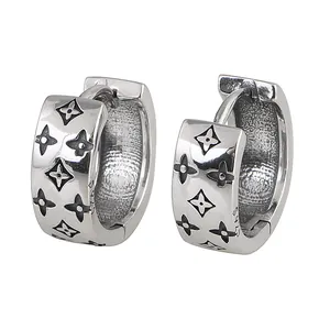 Detailed view of silver hoop earrings with engraved floral patterns and S925 hallmark