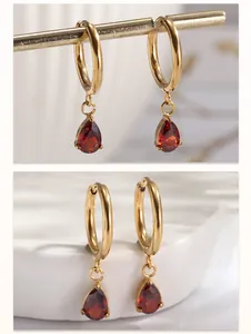 Vue détaillée de boucles d'oreilles en acier doré avec zircons rouges en forme de goutte