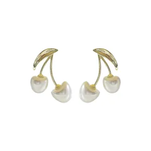 Élégantes boucles d'oreilles cerises dorées avec perles baroques sur un fond blanc pur.
