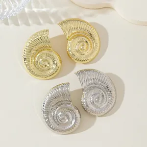 Detalle macro que muestra los brillantes pendientes de caracola en oro y plata