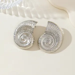 Primer plano de pendientes de concha de nautilo plateados con texturas en espiral.