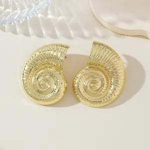 Vista macro de pendientes de concha de nautilo dorados con texturas de estilo playero bohemio