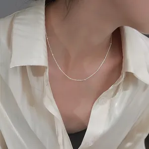 Nahaufnahme einer minimalistischen Silberperlenkette an einem weißen Seidenhemd