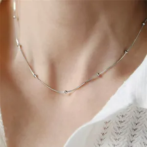 Nahaufnahme einer eleganten silberfarbenen Schlangenkette mit zierlichen, kleinen Perlen