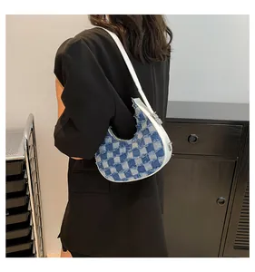 Stylish blue denim checkered crescent bag shown as a trendy underarm shoulder accessory