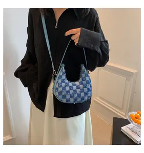 Close-up detail of trendy blue denim checkerboard crescent shoulder bag on a model