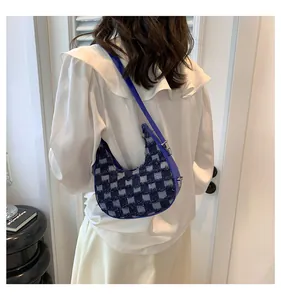 Fashionable blue checkered crescent underarm bag shown as a stylish accessory on a white shirt.