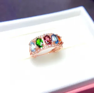 Détail d'une bague en or rose avec cinq pierres précieuses ovales colorées dans une boîte