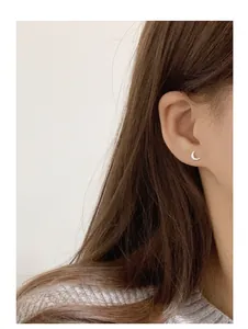 Detail shot of a model wearing a minimalist 999 silver crescent moon stud earring