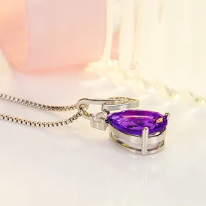 Macro view of teardrop purple pendant necklace with leaf design and sparkly stones.