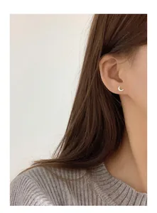Delicate 999 silver crescent moon stud earring with screw back shown on female ear