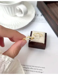 Detaillierte Nahaufnahme eines zarten hohlen Kronenrings in Goldoptik, handgehalten