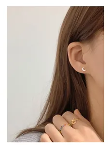 Close-up of a minimalist 999 silver crescent moon stud earring worn by an Asian model
