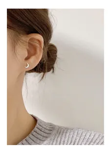 Minimalist crescent moon stud earring in 999 silver worn on model's ear detail.
