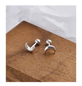 Macro detail of S999 silver crescent moon stud earrings with screw-back on wood.