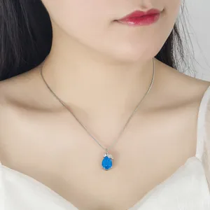 Close-up of elegant silver necklace featuring blue water-drop pendant with leaf accent
