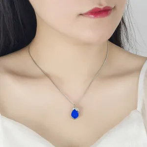 Close-up of elegant blue water-drop pendant necklace with rhinestone leaf detail on neck.