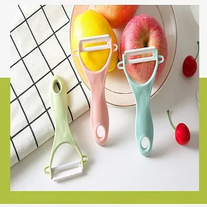 Macro view of three colorful ceramic Y-shaped fruit and vegetable peelers on a plate