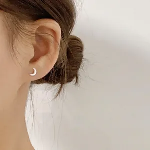 Minimalist 999 sterling silver crescent moon stud earring shown on a model's ear lobe