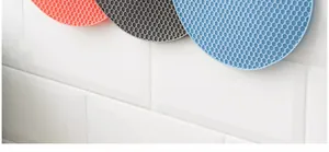 Gros plan de dessous de plat en silicone nid d'abeille sur un mur carrelé.