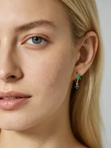 Détail d'une boucle d'oreille dorée avec un pendentif fleur en zircon vert sur modèle