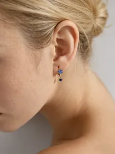 Vue détaillée de boucles d'oreilles fleur en zircon bleu sur modèle en argent s925 massif