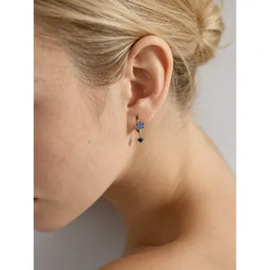 Élégantes boucles d'oreilles fleur en argent S925 avec zircon bleu sur un modèle féminin