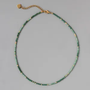 Dettaglio di una collana di perle in pietra naturale verde con accenti dorati.