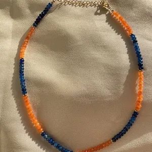 Dettaglio ravvicinato di perle di pietra naturale sfaccettate blu e arancioni su collana.