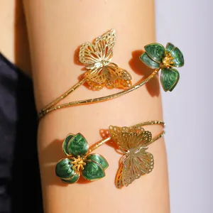 Close-up detail of an adjustable gold-tone arm cuff with green enameled flowers and butterflies.