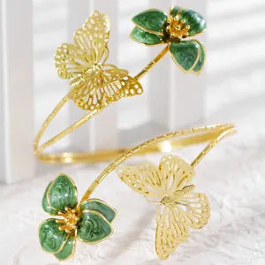 Detail view of the intricate green enamel flower and gold butterfly on adjustable arm cuff