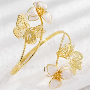Close-up of elegant gold-toned armlet featuring butterfly and white floral motifs