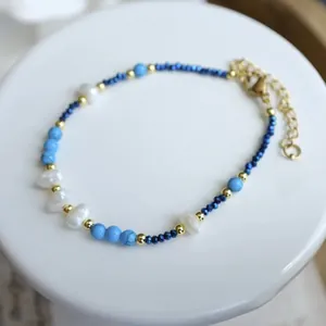 Close-up detail of a blue turquoise and pearl beaded bracelet on a white display stand