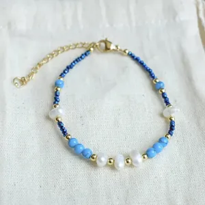 Detailed view of handmade beaded bracelet with blue stones, pearls, and gold accents.