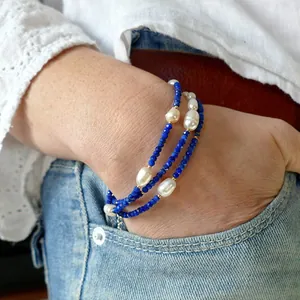 Detail of blue lapis and white pearl stacked bracelets on wrist