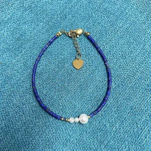 Close-up detail of blue natural stone beaded bracelet with pearl and gold heart charm
