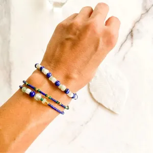 Detailed view of layered blue natural stone and turquoise beaded bracelets on a wrist.