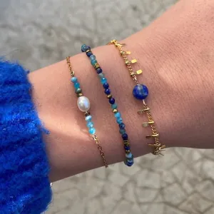 Detailed view of layered blue natural stone bracelets with pearls and gold accents