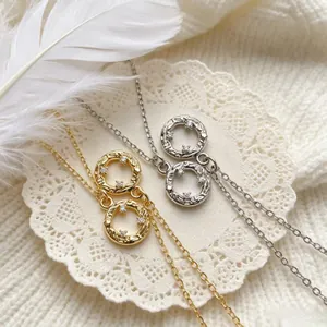 Close-up detail of vintage sun zircon interlocking ring pendants in gold and silver.