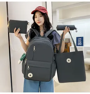 Set of four minimalist dark grey student bags including backpack and tote shown on model