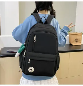 Detailed back view of a minimalist black student backpack worn by a casual female model.