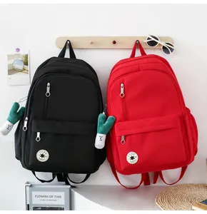A pair of minimalist black and red student backpacks hanging on a wooden wall rack
