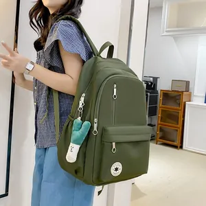 Green Korean style lightweight student backpack with large capacity and cute keychain.