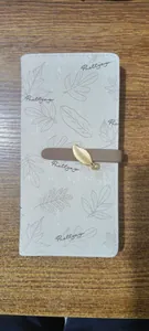 Vista detallada de la cartera larga de cuero PU beige con estampado de hojas y dije de metal