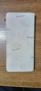 Vista vertical de una cartera larga de cuero PU crema con patrones de hojas y letras