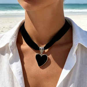 Gedetailleerde close-up van een zwarte fluwelen hartjes-choker gedragen op het strand