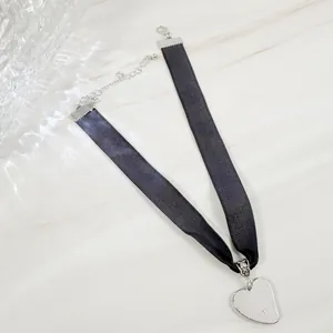 Detailweergave van een zwarte fluwelen choker met een zilveren hartvormige hanger