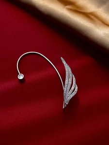 Close-up view of a minimalist silver leaf ear cuff featuring shiny cubic zirconia on red velvet
