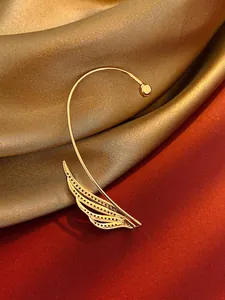 Macro detail of elegant golden leaf-shaped ear cuff with shimmering zircon stone inlay