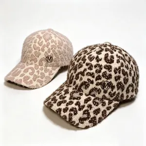 Detail view of plush leopard print baseball caps with metallic M logo for winter.